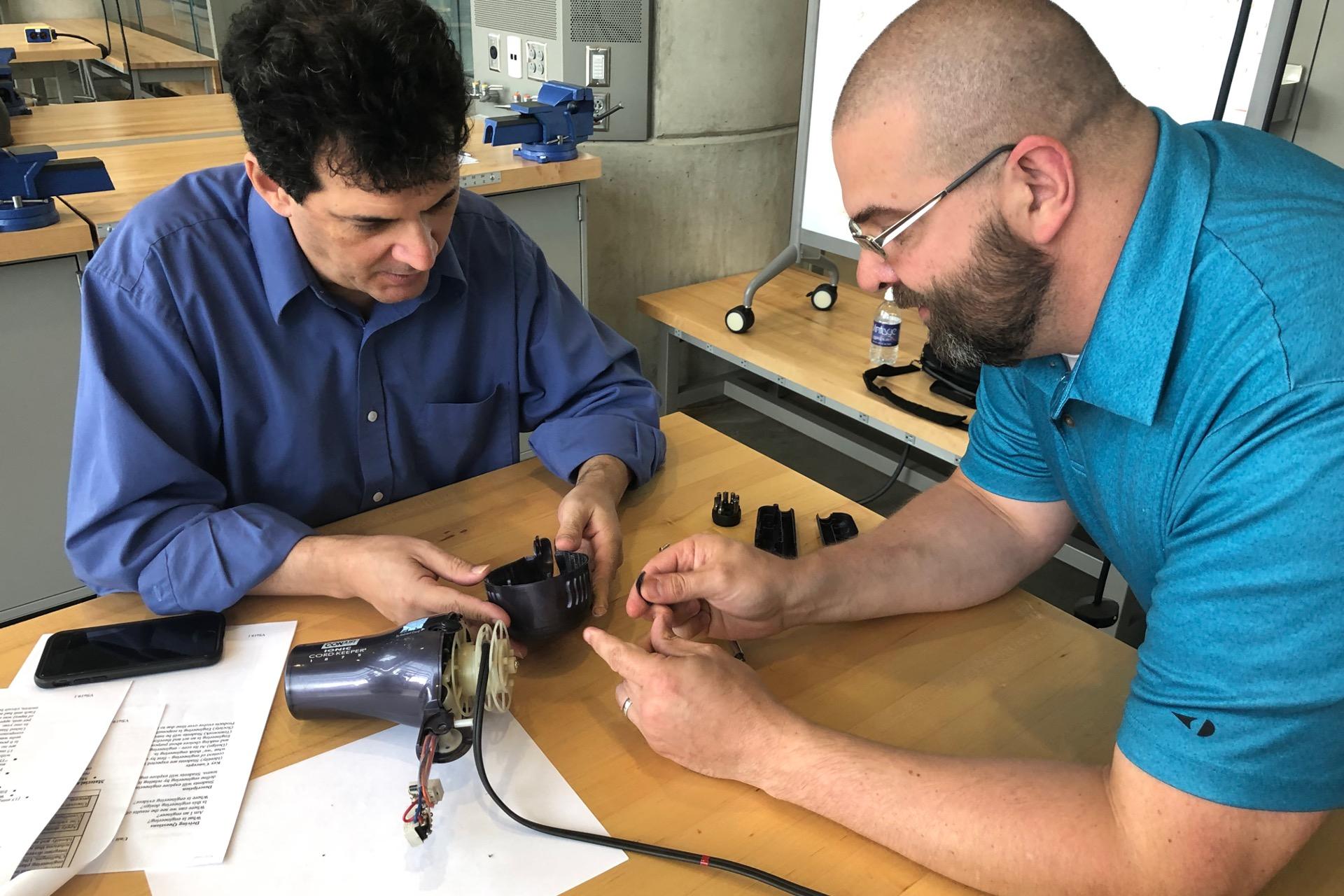 Two teachers modifying components of a hair blower as part of a project in a school laboratory.